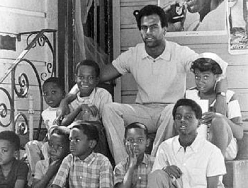 Huey Newton surrounded by youth of East Oakland community, August 1970.