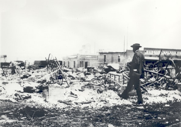 Tulsa Race Riot ruins, an African American man with a camera surveying the rubble.