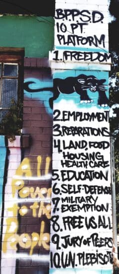A photograph of a colorful mural depicting the Black Panther Party's 10 Point Program, as seen on the side of Marcus Books in Oakland, California.