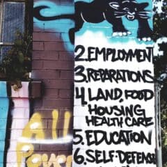 A photograph of a colorful mural depicting the Black Panther Party's 10 Point Program, as seen on the side of Marcus Books in Oakland, California.