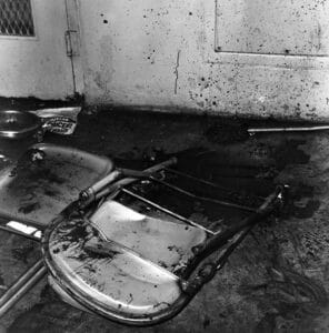 Raiford prison uprising aftermath, showing overturned chairs and blood on the wall.
