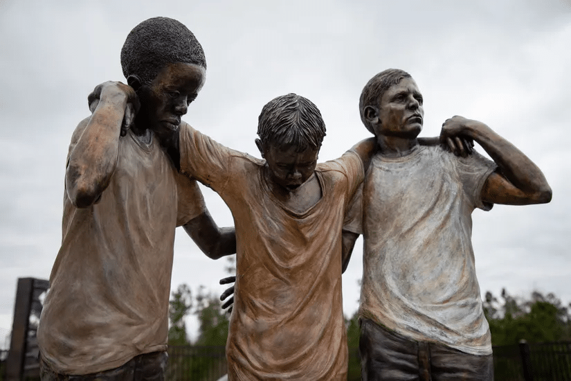 a statue of three boys holding up the one in the middle