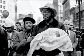 A young Black couple walking with their newborn child in the first national Martin Luther King Jr. holiday in San Francisco, circa 1986.