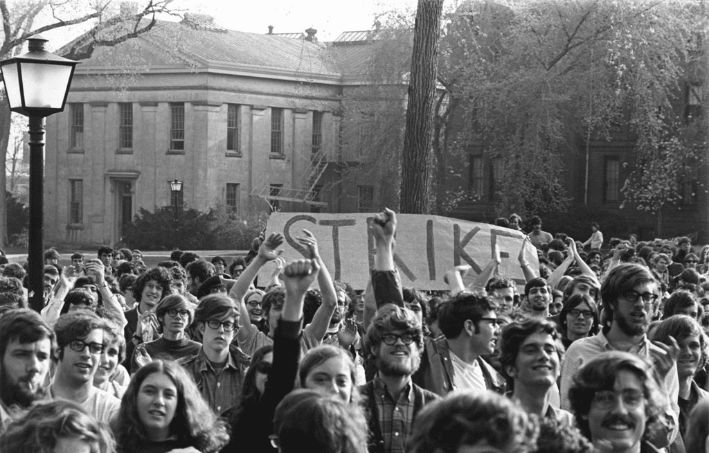 Brown University students on strike in 1970, holding signs, protesting in a large crown on campus.